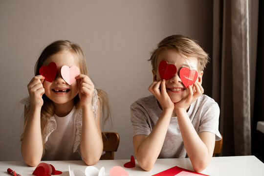 Kids painting red valetine heart card on table at home