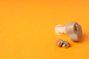 Concept of health care with hearing aid on orange background