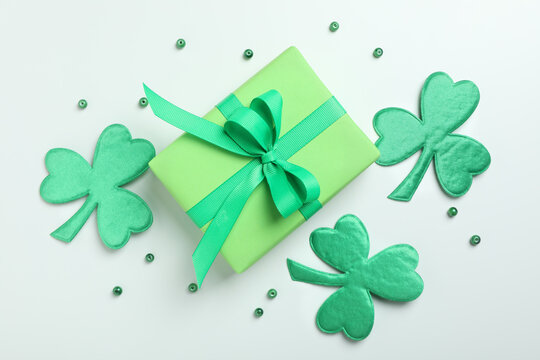 Clover leaves, gift box and beads on white background