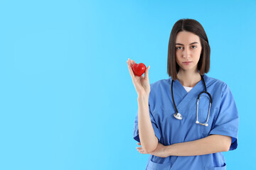 Attractive female trainee nurse on blue background