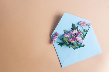 Blue pastel envelope on light yellow background with flowers message invitation concepts