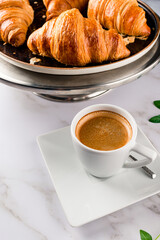 Breakfast with croissants, green leaves and black coffee composition