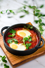 Shakshuka in a Cast Iron Pan. Middle eastern style eggs in tomato and pepper sauce with parsley for breakfast.