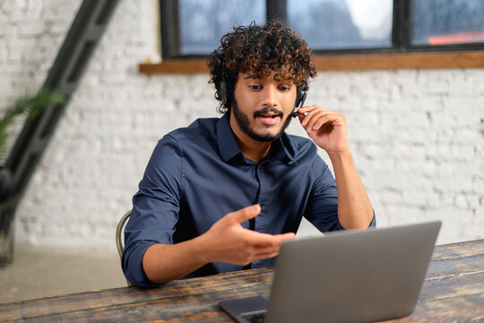 Remote job, technology and people concept. Happy smiling man with headset and laptop computer having video conference at home office. Businessman in headphones consulting client