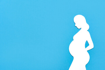 Concept of pregnancy. Paper silhouette of a pregnant woman on a blue background. Flat lay, place...