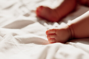 Obraz na płótnie Canvas closeup of the bare feet of a newborn baby lying on a white sheet. High quality photo