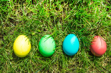 Four painted and decorative Easter eggs in the grass. Top view, copy space