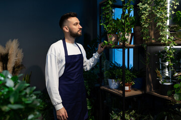 Male florist In the garden center against the background of potted plants
