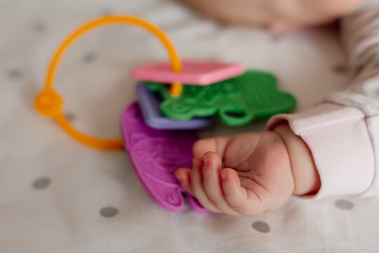 close-up of a newborn baby's hand with a toy. newborn baby covered with blanket sleeps in his crib with his favorite toy. products for children. space for text. High quality photo