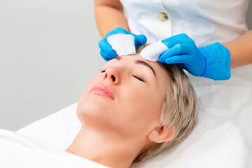 Obraz na płótnie Canvas A professional cosmetologist does a mechanical cleaning of the client's face. The procedure for getting rid of acne. The concept of salon skin care