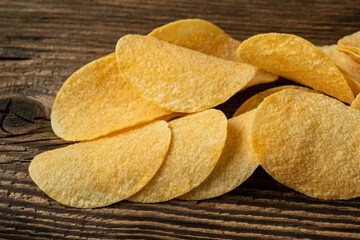 Potato chips on a wooden background. Salty crisps scattered on a table.