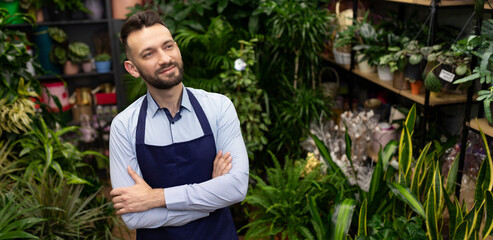 male gardener wearing an apron against the background of potted plants