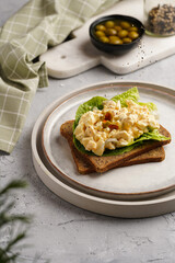 Protein bread sandwich with greens, olives and egg salad on scandi plate on concrete tray