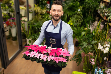 Fototapeta premium botanist against the background of the garden center with a tray of potted plants in his hands