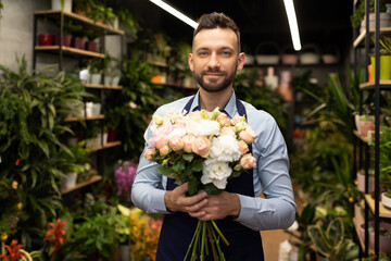businessman florist with a bouquet in his hands on the background of the flower shop