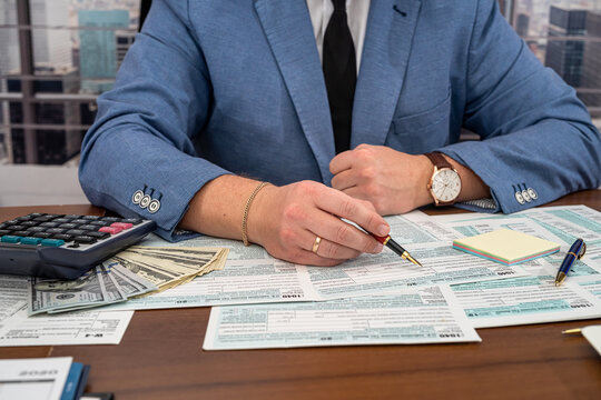 a business man in a jacket fills out tax forms and makes calculations at the table.