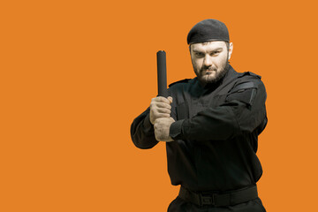 Fototapeta na wymiar Bodyguard. Mercenary. Private security. Defender. A male guard in a black uniform and a cap took up a defensive position, holding a baton with both hands