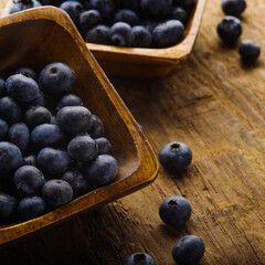 Blue blueberries in bowls. Wooden texture. Close-up. Forestry and agriculture, seasonal berries, vitamins, antioxidants, ecology, environmental protection, ingredient for pies, cakes, fresh juices.