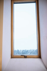 wooden window in the wall in the attic room. Winter outside the window