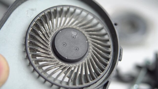 Laptop dirty CPU fan in hand. Dusty cooling system. Macro. Used plastic device cooler