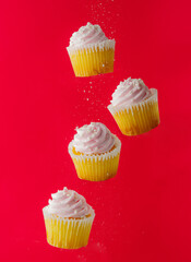 Muffins with cream on a red background in a frozen flight. Creative composition. There are no people in the photo. Minimalism. Restaurant, hotel, confectionery, advertising.