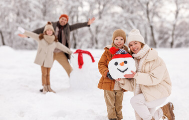 Cheerful family parents with kids in snowy winter park have fun and actively relax outdoors