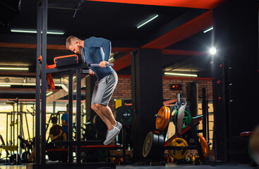 Athletic man trains in the gym with equipment. Copy space. Dips. The concept of fitness and wellness