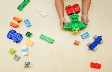 Close up kids hand playing with toy airplane and toy bricks  on a wood background.