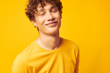 Young curly-haired man yellow t-shirt glasses fashion hand gestures isolated background unaltered