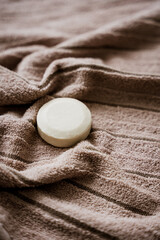 Fototapeta na wymiar Eine weiße runde Seife auf einem braunen Handtuch. Wellness, plastikfrei.