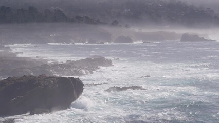 Rocky craggy ocean beach, Point Lobos landscape, California coast, USA. Big sea water waves crashing on cliffs. Monterey nature near Big Sur, 17-mile drive. Seascape and mountains, foggy misty weather