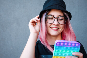 Young Girl Holding pink Pop It Fidget Toy in hands. Teen Playing