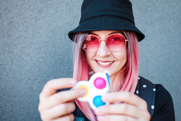Young Girl Holding pink Pop It Fidget Toy in hands. Teen Playing