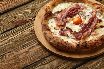 Carbonara pizza with bacon and egg on wooden background