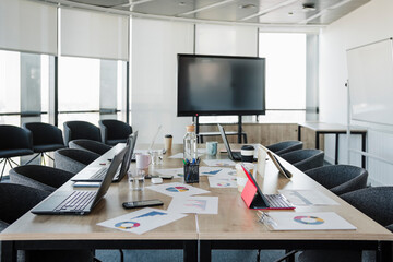 Laptops and graphs kept on conference table in empty meeting room