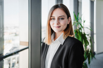 Beautiful working woman smiling near window in office
