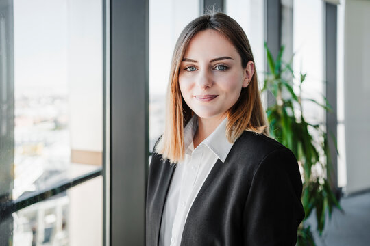 Beautiful working woman smiling near window in office