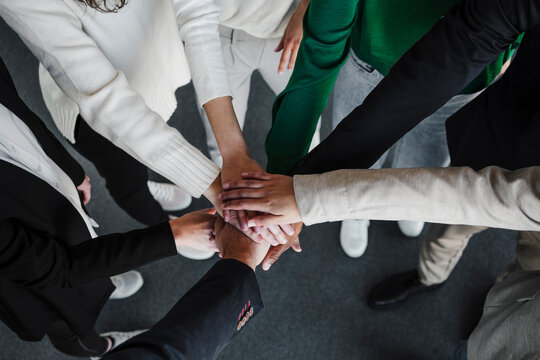 Businesswomen and businessmen stacking hands in office