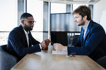 Businessman giving pen to client for signing contract in office