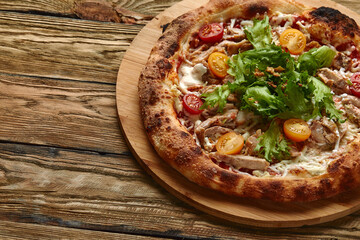 Pizza Caesar. Pizza with chicken, tomato, cheese and lettuce on wooden board. Top view. Free space for your text. Delivery food