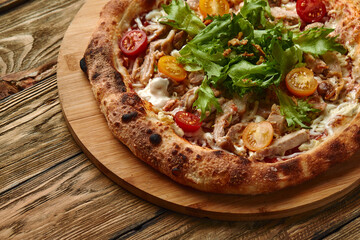 Pizza Caesar. Pizza with chicken, tomato, cheese and lettuce on wooden board. Top view. Free space for your text. Delivery food