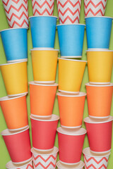 Multicolored eco paper party cups on green background