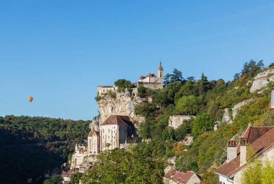 France, Lot, Rocamadour, View of cliffside town with hot air balloon in background