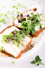 Microgreen sprouts on a sandwich on a light background. Sandwiches made of cheese, bread and microgreens