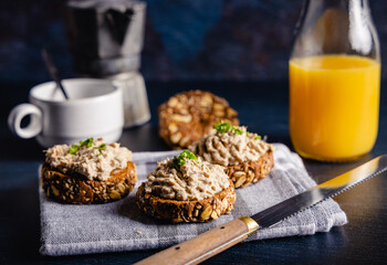 Homemade vegan tuna spread. Homemade vegan tuna spread served on whole grain bread, with a coffee and orange juice on the side. On a white table top.