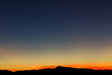 Heaven at early morning with copy space. Sunset, sunrise backdrop.Predawn clear sky with orange horizon and blue atmosphere. Smooth orange blue gradient of dawn sky.