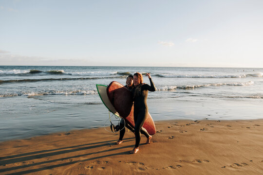 Cheerful female surfers with surfboards walking on sand at beach, Gran Canaria, Canary Islands