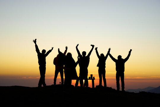 Silhouette friends with arms raised at sunset, Sochi, Krasnaya Polyana, Russia