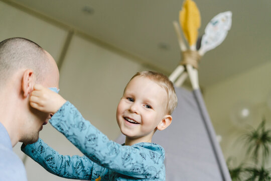 Smiling son putting birthday prop to father at home