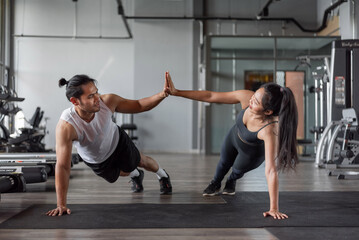 Fototapeta na wymiar Asian woman and asian man exercise in fitness. Healthy couple doing abs exercise together in gym.